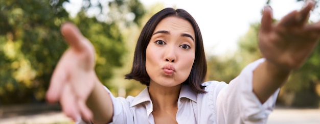 Photo gratuite les gens et la connexion mobile heureuse jeune femme asiatique prend un selfie sur smartphone tient la caméra avec