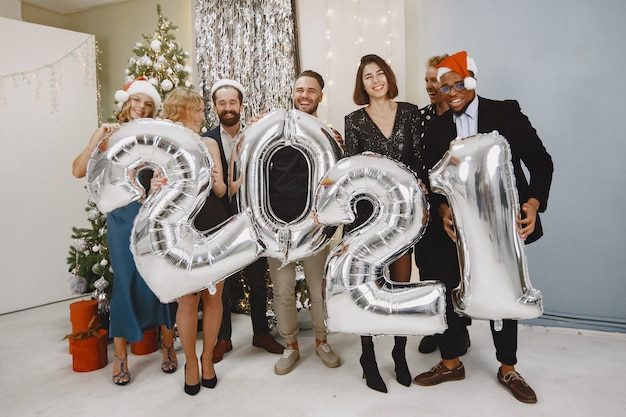 Les gens dans une décoration Christman. Homme en costume noir. Célébrations de groupe Nouvel an. Les gens avec des ballons 2021.