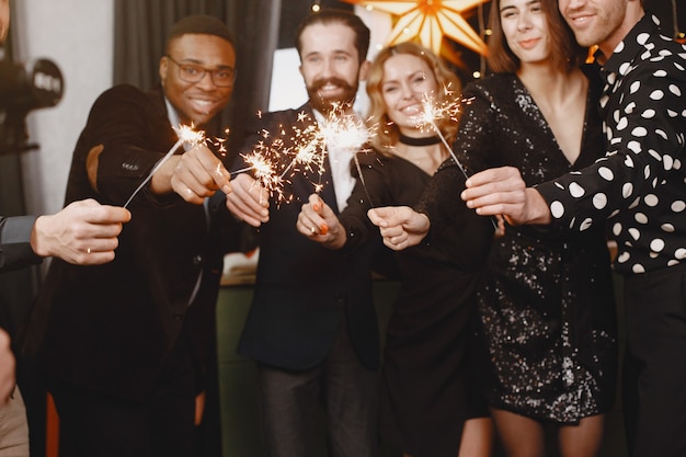 Les gens dans une décoration Christman. Homme en costume noir. Célébrations de groupe Nouvel an. Les gens avec des lumières du Bengale.