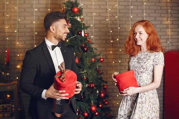 Les gens dans une décoration Christman. Homme en costume noir. Femme avec boîte rouge.