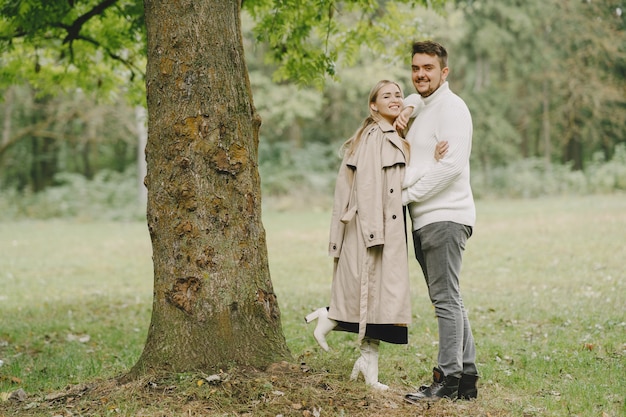 Les gens dans un parc. Femme en manteau marron. Homme dans un pull blanc.