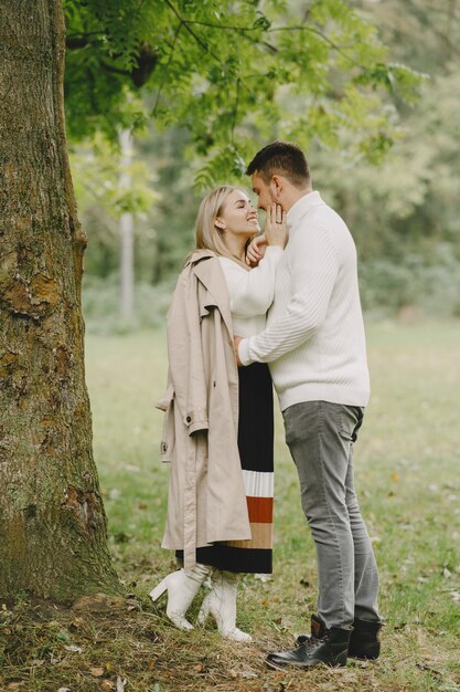 Les gens dans un parc. Femme en manteau marron. Homme dans un pull blanc.