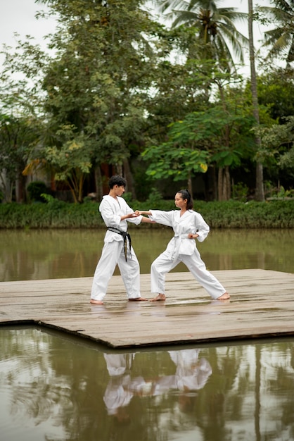 Photo gratuite les gens à l'extérieur dans la nature s'entraînent pour le taekwondo