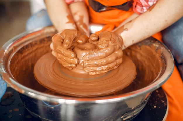 Les gens faisant une vaze d'une argile sur une machine de poterie