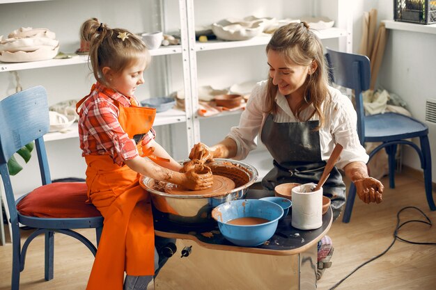 Les gens faisant une vaze d'une argile sur une machine de poterie