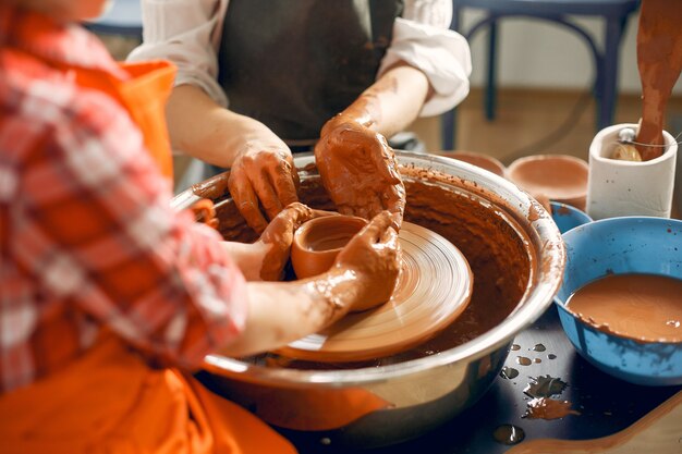 Les gens faisant une vaze d'une argile sur une machine de poterie