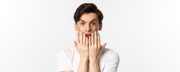 Les gens lgbtq et le concept de beauté Bel homme gay montrant du vernis à ongles bleu sur les ongles et regardant la caméra ont une manucure debout sur fond blanc