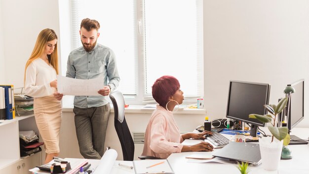 Les gens lisant le projet près de collègue de travail