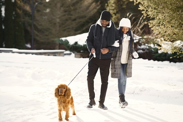 Les gens marchent dehors. Jour d'hiver. Couple africain avec chien.