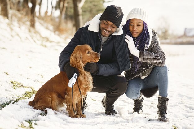 Les gens marchent dehors. Jour d'hiver. Couple africain avec chien.