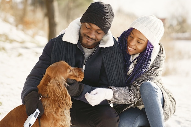 Les gens marchent dehors. Jour d'hiver. Couple africain avec chien.