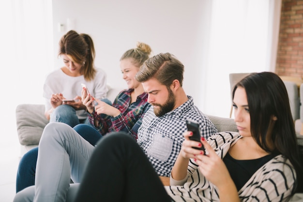 Les gens obsédés par les téléphones assis sur le canapé