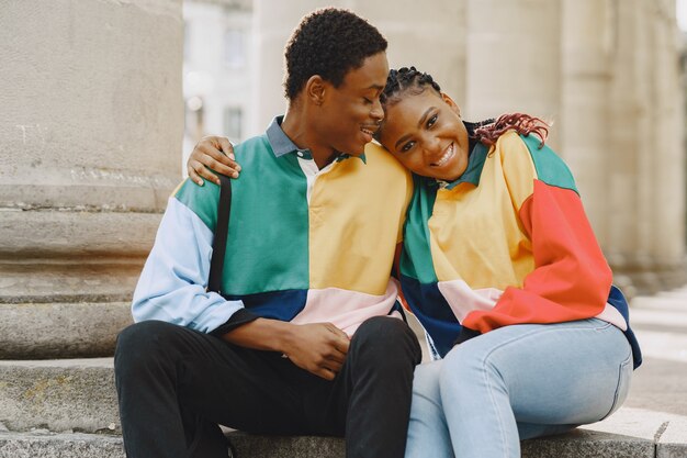 Des gens portant des vêtements identiques. Couple africain dans la ville d'automne. Des gens assis dans une rue.