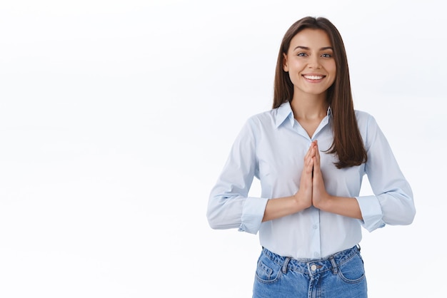 Gens de positivité et concept de style de vie Soulagée heureuse jolie jeune femme en chemisier bleu serrer les mains près de la poitrine en geste de prière souriant regardant la caméra priant ou implorant une faveur