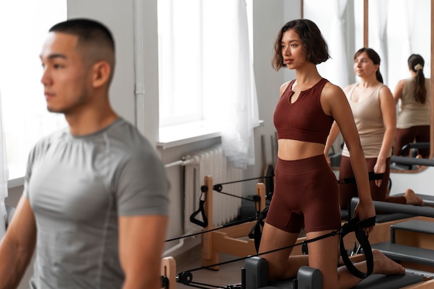 Photo gratuite les gens qui suivent des cours de pilates réformateur