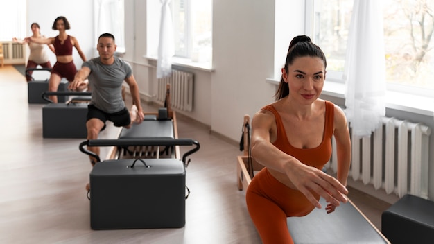 Photo gratuite les gens qui suivent des cours de pilates réformateur