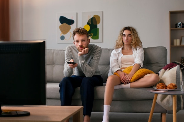 Photo gratuite les gens regardent la télévision sur le canapé en plein coup