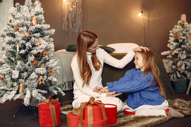 Les gens réparent pour Noël. Mère jouant avec sa fille. La famille se repose dans une salle de fête. Enfant dans un pull bleu.