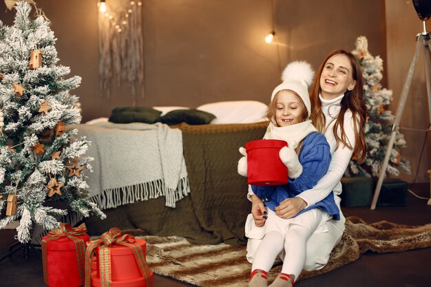 Les gens réparent pour Noël. Mère jouant avec sa fille. La famille se repose dans une salle de fête. Enfant dans un pull bleu.