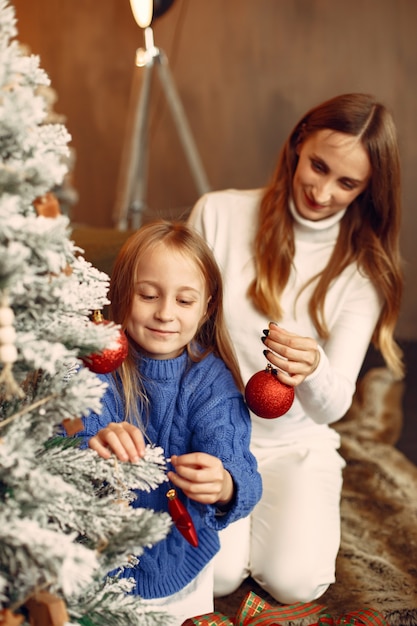 Les gens réparent pour Noël. Mère jouant avec sa fille. La famille se repose dans une salle de fête. Enfant dans un pull bleu.