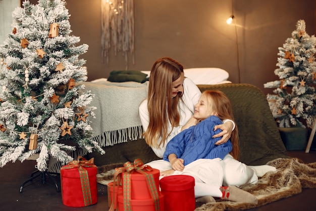 Les gens réparent pour Noël. Mère jouant avec sa fille. La famille se repose dans une salle de fête. Enfant dans un pull bleu.