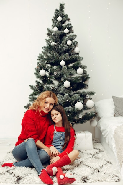 Les gens réparent pour Noël. Mère jouant avec sa fille. La famille se repose dans une salle de fête. Enfant dans un pull rouge.