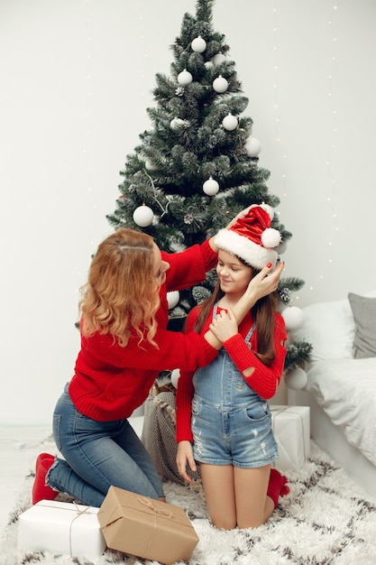 Les gens réparent pour Noël. Mère jouant avec sa fille. La famille se repose dans une salle de fête. Enfant dans un pull rouge.