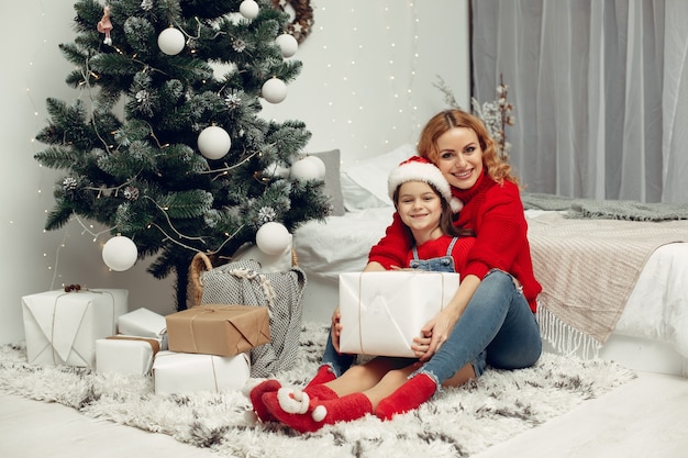 Les gens réparent pour Noël. Mère jouant avec sa fille. La famille se repose dans une salle de fête. Enfant dans un pull rouge.