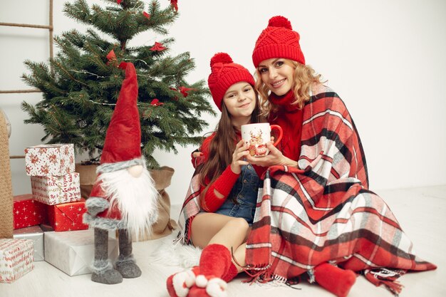 Les gens réparent pour Noël. Mère jouant avec sa fille. La famille se repose dans une salle de fête. Enfant dans un pull rouge.