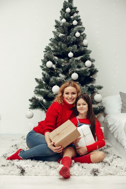 Les gens réparent pour Noël. Mère jouant avec sa fille. La famille se repose dans une salle de fête. Enfant dans un pull rouge.