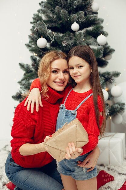 Les gens réparent pour Noël. Mère jouant avec sa fille. La famille se repose dans une salle de fête. Enfant dans un pull rouge.