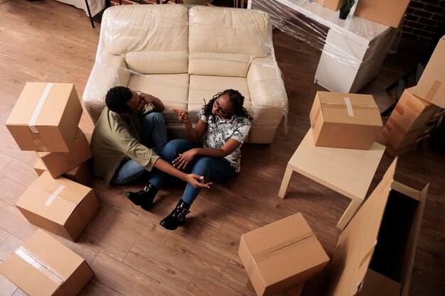 Des gens romantiques se détendent ensemble sur le sol du salon, parlent de décorations et de la future famille. Profiter d'un déménagement et faire une pause après avoir emménagé, réussite relationnelle. Vue de dessus de.