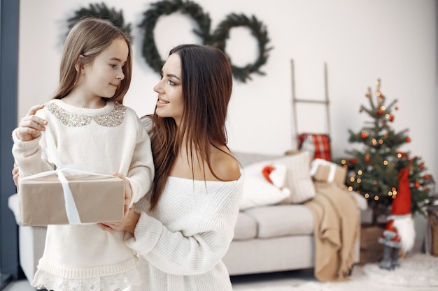 Les gens se préparent pour Noël. Mère jouant avec sa fille. La famille se repose dans une salle festive. Petite fille en robe blanche.