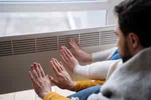 Photo gratuite les gens se réchauffent les mains avec un radiateur