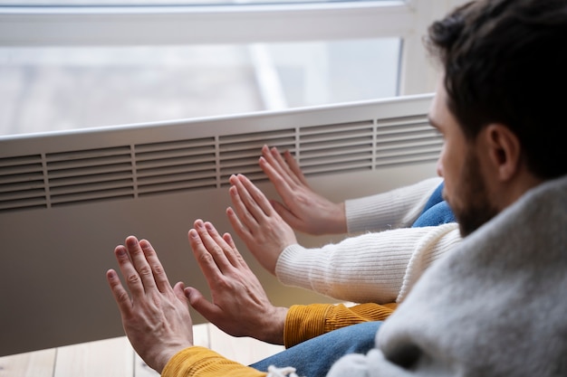 Les gens se réchauffent les mains avec un radiateur