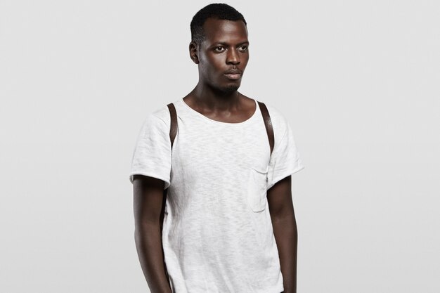 Les gens et le style de vie. Séduisante jeune étudiante hipster africaine portant un sac à dos en cuir et un T-shirt blanc avec espace de copie pour votre publicité.