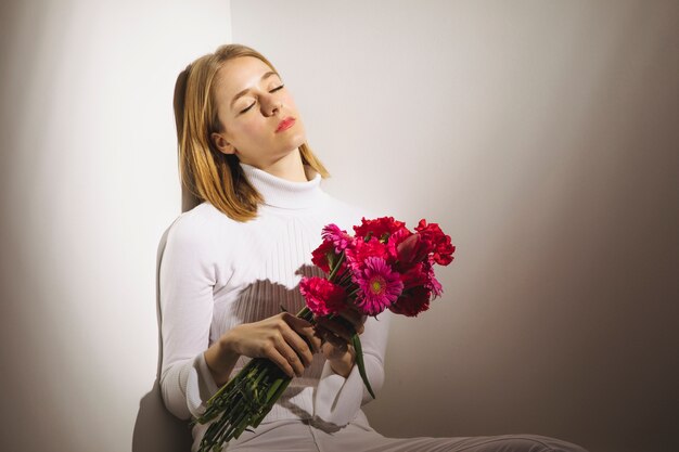 Gentil femme assise avec bouquet de fleurs roses