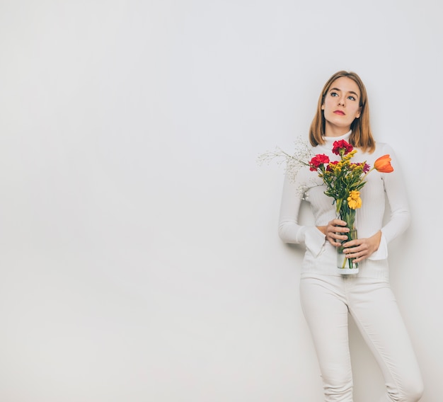 Gentil jeune femme avec des fleurs dans un vase