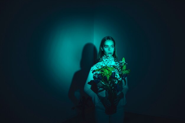 Gentil jeune femme avec des fleurs dans un vase