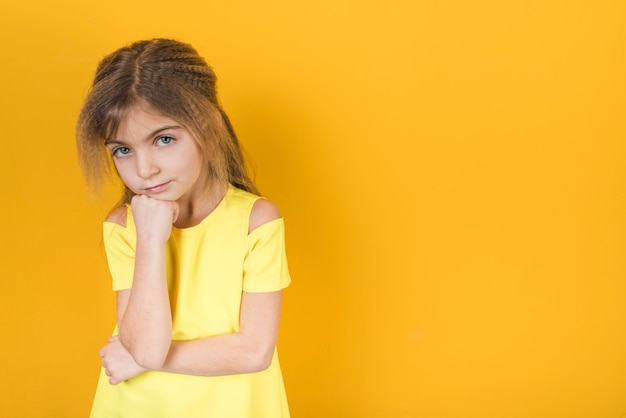 Gentil petite fille debout sur fond jaune