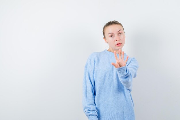 La gentille fille montre un geste d'arrêt sur fond blanc