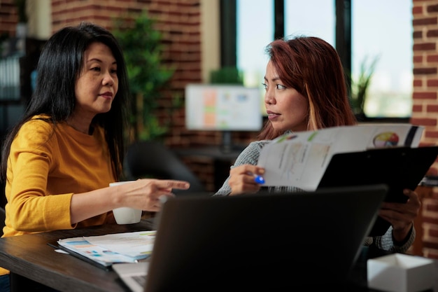 Gestionnaire collaborant avec une femme d'affaires lors d'une réunion d'affaires discutant de la stratégie de l'entreprise dans le bureau de démarrage. Femmes d'affaires analysant des graphiques de gestion travaillant sur un projet de partenariat