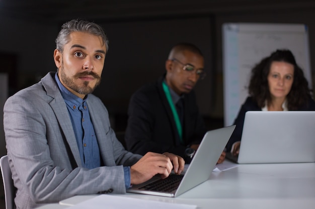 Gestionnaire concentré assis à table et regardant la caméra