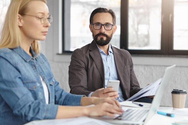 Gestionnaire de femme blonde heureuse a une conversation avec un collègue masculin