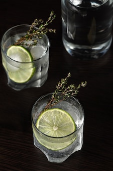 Gin tonic avec une tranche de citron vert et des brins de thym