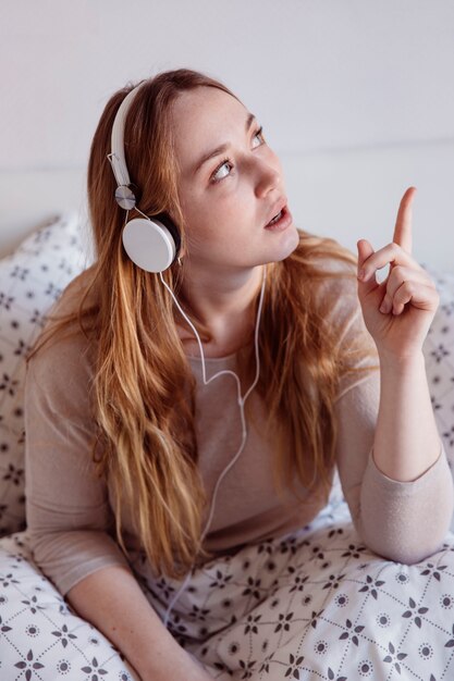 Ginger femme écoutant de la musique dans son lit