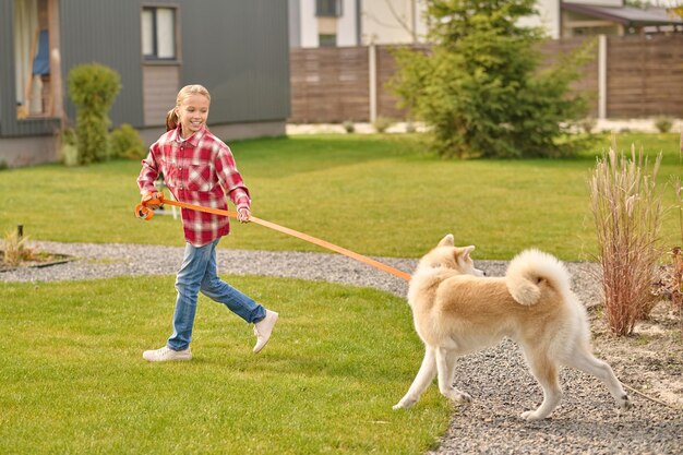 Girl holding laisse courir en regardant chien