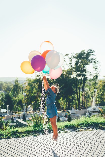 Girl, tenue, coloré, ballons, étirage, ciel