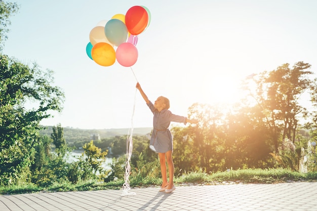 Girl, tenue, coloré, ballons, étirage, ciel