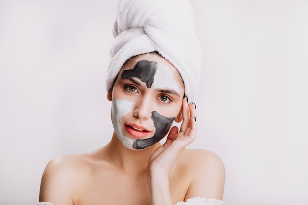 Girl utilise de l'argile blanche et noire pour améliorer et nettoyer la peau. Portrait du modèle en serviette après avoir lavé ses cheveux.